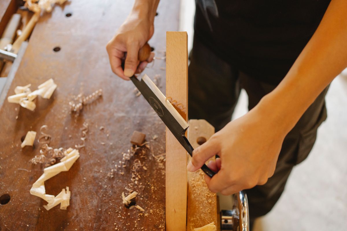 Craftsman working on wood joint with chisel and shavings on bench